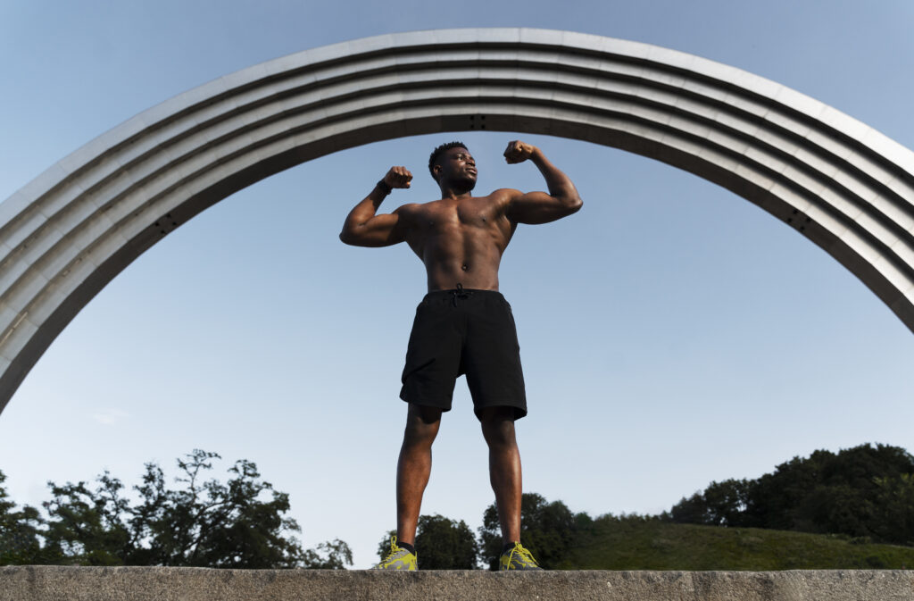 a man flexing his muscles under a arch, demonstrating achievement through positive mindset